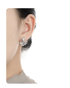 Close-up of sparkling ginkgo leaf stud earring with crystals on a female ear