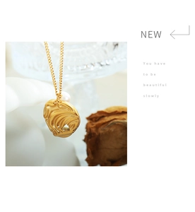 Close-up of golden irregular lava-textured pendant necklace with a single freshwater pearl