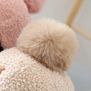 Detail of soft cream teddy fleece fabric and khaki faux fur pompom on children's baseball cap