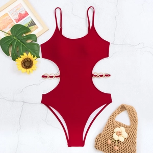 Close-up of deep red one-piece swimsuit with gold ring details and cut-out waist design