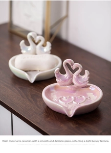 Macro view of ceramic swan soap dishes with iridescent pearl glaze and heart relief