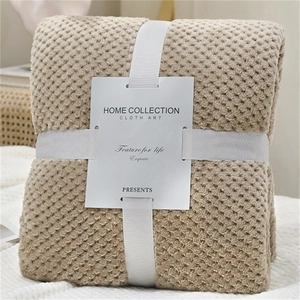 Thick light khaki waffle weave flannel blanket folded with a decorative gift ribbon