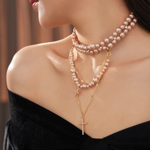 Detail of layered champagne pearl necklace with gold cross pendants and crystal accents