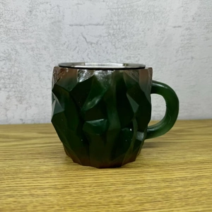 Detailed view of the dark green faceted geometric mug with a durable stainless steel rim