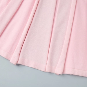 Detailed macro view of pleated pink knit fabric showing fine texture and vertical folds
