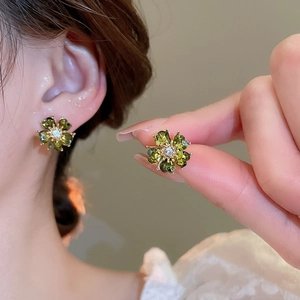 Macro detail of dark green flower stud earrings with zircon petals and gold base