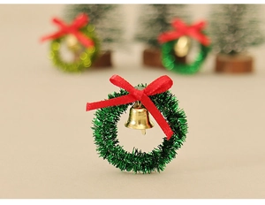 Macro detail of mini green Christmas wreath with a red bow and a golden bell ornament