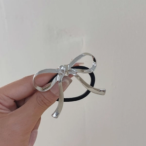 Detail of silver hammered metal bow hair tie with high-elastic black rubber band