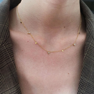 Detailed view of dainty gold necklace with triangular geometric pendants and sparkling zircons