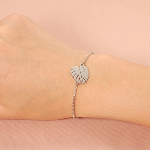 Minimalist silver stainless steel leaf bracelet with adjustable chain on silk background