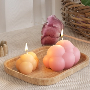Candele profumate a forma di nuvola arancione e rosa opaco su vassoio in legno