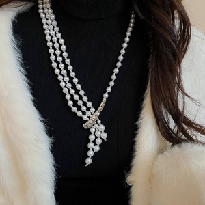 Detail of multi-layer pearl necklace with silver textured clasp on a black sweater