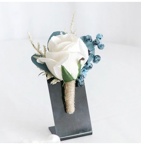 Detail of white silk rose boutonniere with blue berries and rustic twine-wrapped stem
