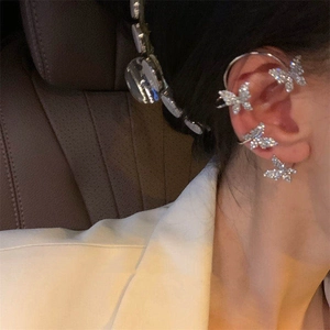 Close-up of a silver butterfly ear cuff with sparkling rhinestones worn on a female ear