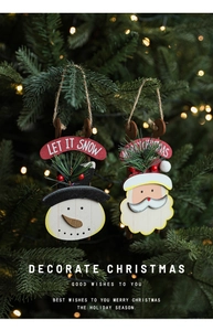 Detail of wooden snowman and Santa sled ornaments hanging on a Christmas tree branch