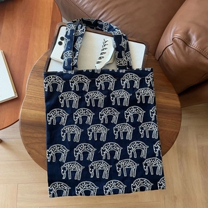 Detail of dark blue canvas tote bag with white sheep embroidery on a wooden table