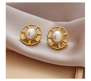 Détail des boucles d'oreilles vintage dorées avec perles ovales sur tissu de soie