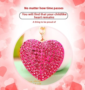 Close-up of pink heart-shaped keychain with shiny rhinestones and golden metal chain
