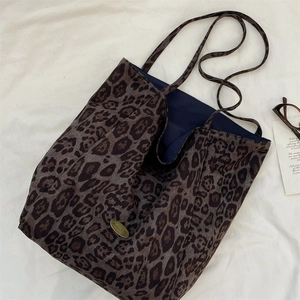Detailed view of leopard print tote bag with gold brand emblem and blue lining