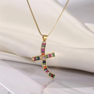Close-up of gold cross pendant with rainbow baguette stones on white silk background