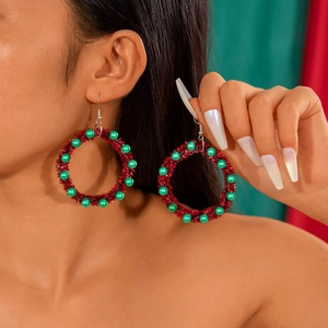 Close-up of red woven hoop earrings with green beads for Christmas accessory detail