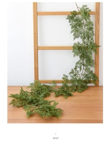 Detail showing artificial dark green cedar garland draped over a wooden ladder for decor