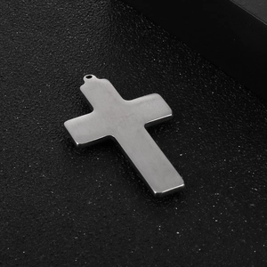 Polished silver stainless steel cross pendant detail on a dark textured background