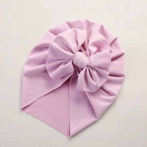 Detailed macro view of pink baby turban hat showing waffle knit texture and large bow