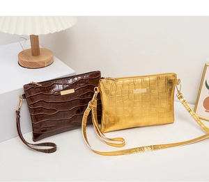 Detail showing dark brown and gold crocodile pattern faux leather shoulder bags on a desk