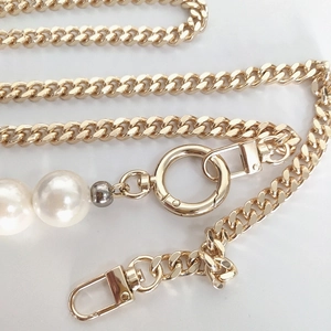 Macro detail of golden metal bag chain with large pearls and lobster clasps for bag upgrade