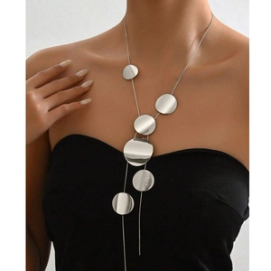 Close-up of long silver necklace with circular geometric pendants on a female model