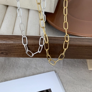 Minimalist 925 sterling silver chain choker in gold and silver finishes on a wooden stand