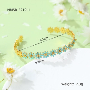 Detail shot of a gold-plated daisy cuff bracelet featuring blue enamel flowers and size marks