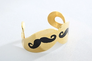 Macro shot of gold mustache open cuff bracelet with brushed metal texture and black detail