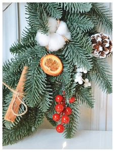 Macro detail of Christmas wreath with pine needles, cotton, cinnamon sticks and red berries