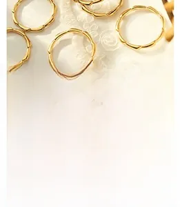 Close-up of golden wavy rings on white lace fabric showing minimalist wave edge design