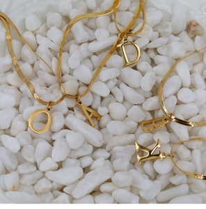 Detail of 18K gold plated flat snake chain necklaces with various initial letter pendants