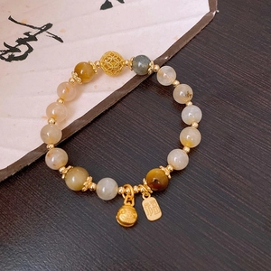 Detailed shot of Chinese style bead bracelet with a Fu character charm and gold bells