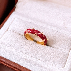 Macro detail of red enamel gold-plated wavy ring with rivets in velvet jewelry box