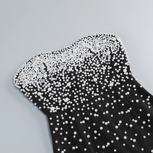 Detail of hand-sewn white pearls in varying sizes on a black strapless evening dress