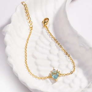 Elegant gold unicorn rainbow bracelet with light blue teardrop gemstone on shell tray