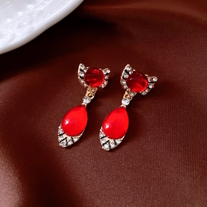 Detail of vintage gold earrings with red teardrop gems and crystals on dark silk