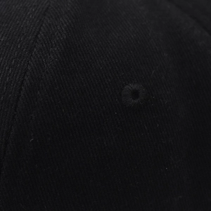 Close-up of black cotton twill fabric showing detailed stitching and embroidered eyelet