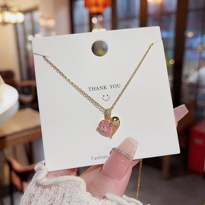 Détail d'un collier pendentif cœur doré avec gemme rose sur carte de présentation