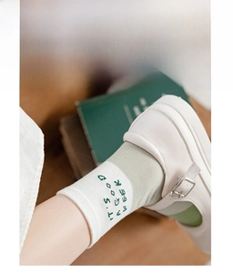 Close-up of green crew socks with white toe and 'IT'S A GOOD WEEK' embroidery detail