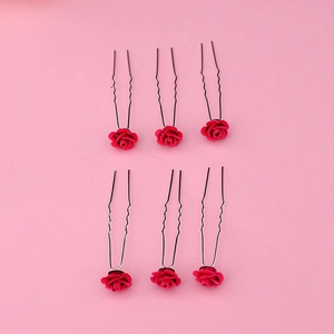 Detail view of 6pcs red fabric rose U-shaped hair pins on a pink background