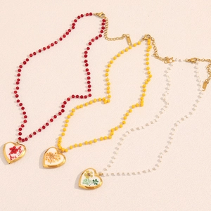 Detail of 18KGP gold necklaces featuring heart-shaped lockets with real dried flowers