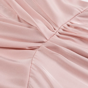 Detail of light pink satin fabric showing elegant pleats and soft silk texture