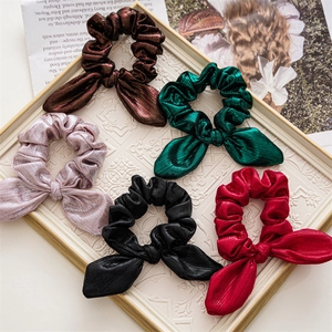 Flat lay of five colorful satin bow hair scrunchies on a vintage decorative tray