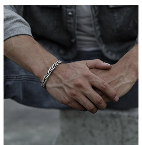 Nahaufnahme einer silbernen Vintage-Armspange mit Kordelmuster am Handgelenk im Retro-Stil